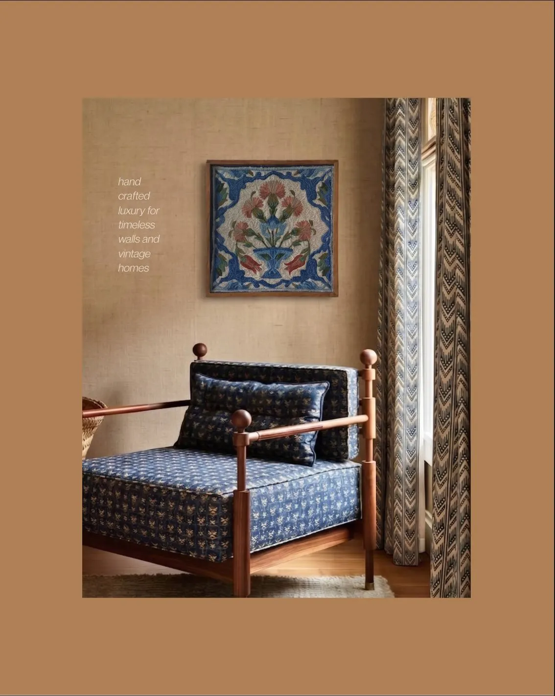 A framed embroidered floral tile hanging above a daybed with indigo cushions