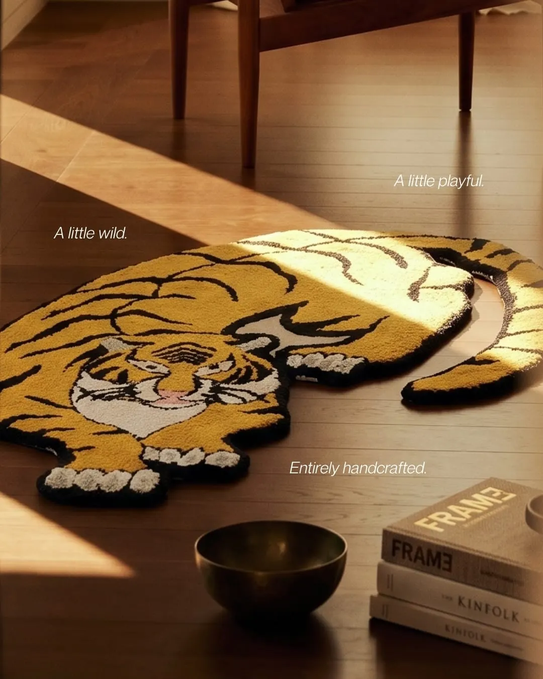 A tiger-shaped tufted rug in mustard, black and white on a wooden floor in warm light. Text reads A little wild, a little playful, entirely handcrafted.
