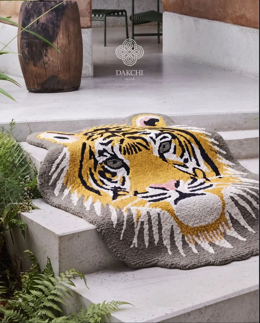 A tiger-face tufted rug draped over white steps among ferns