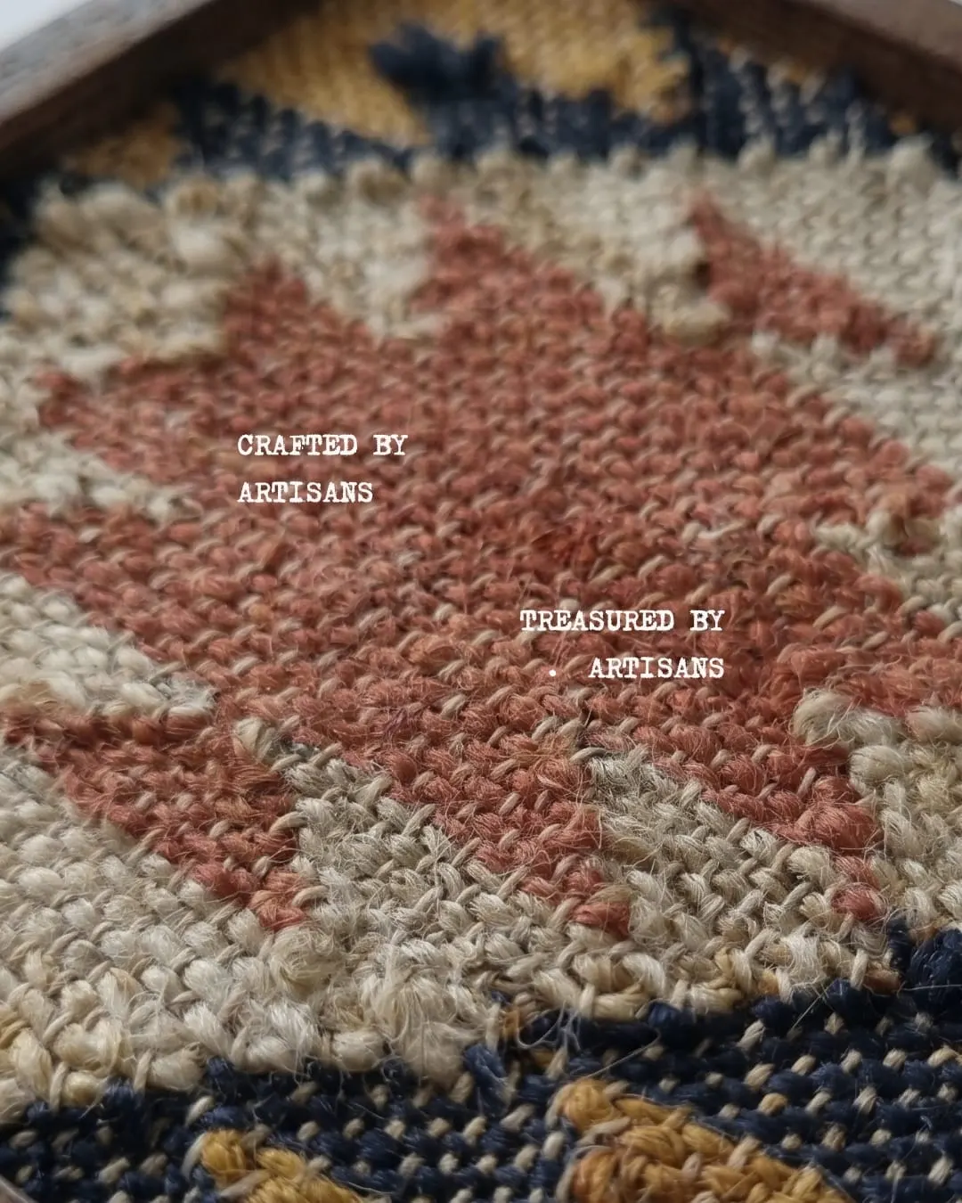 Close-up of a hand-woven texture in rust, cream and navy, with the words Crafted by artisans, treasured by artisans